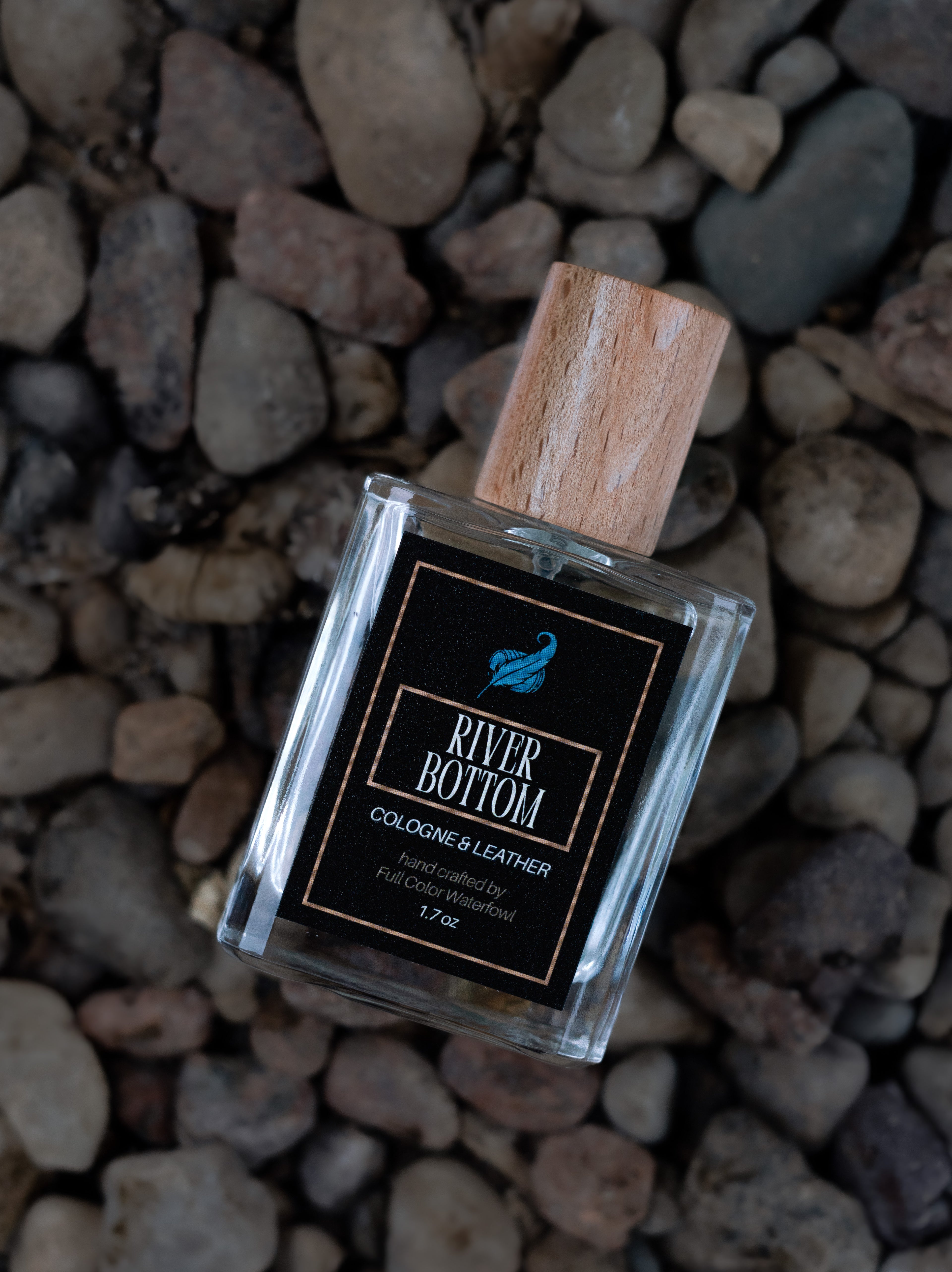 Perfume bottle labeled 'River Bottom' on pebbles